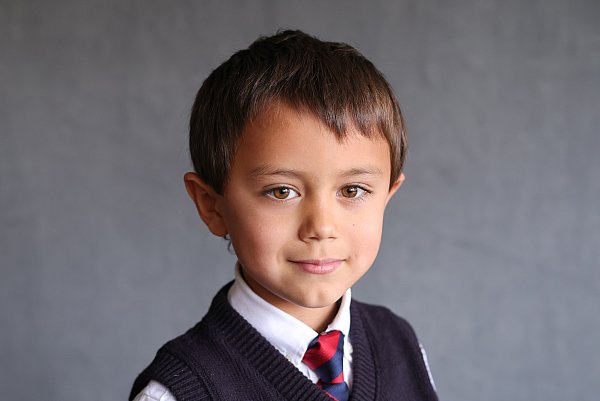 7 year old boy wearing school uniform for class portrait on gray background