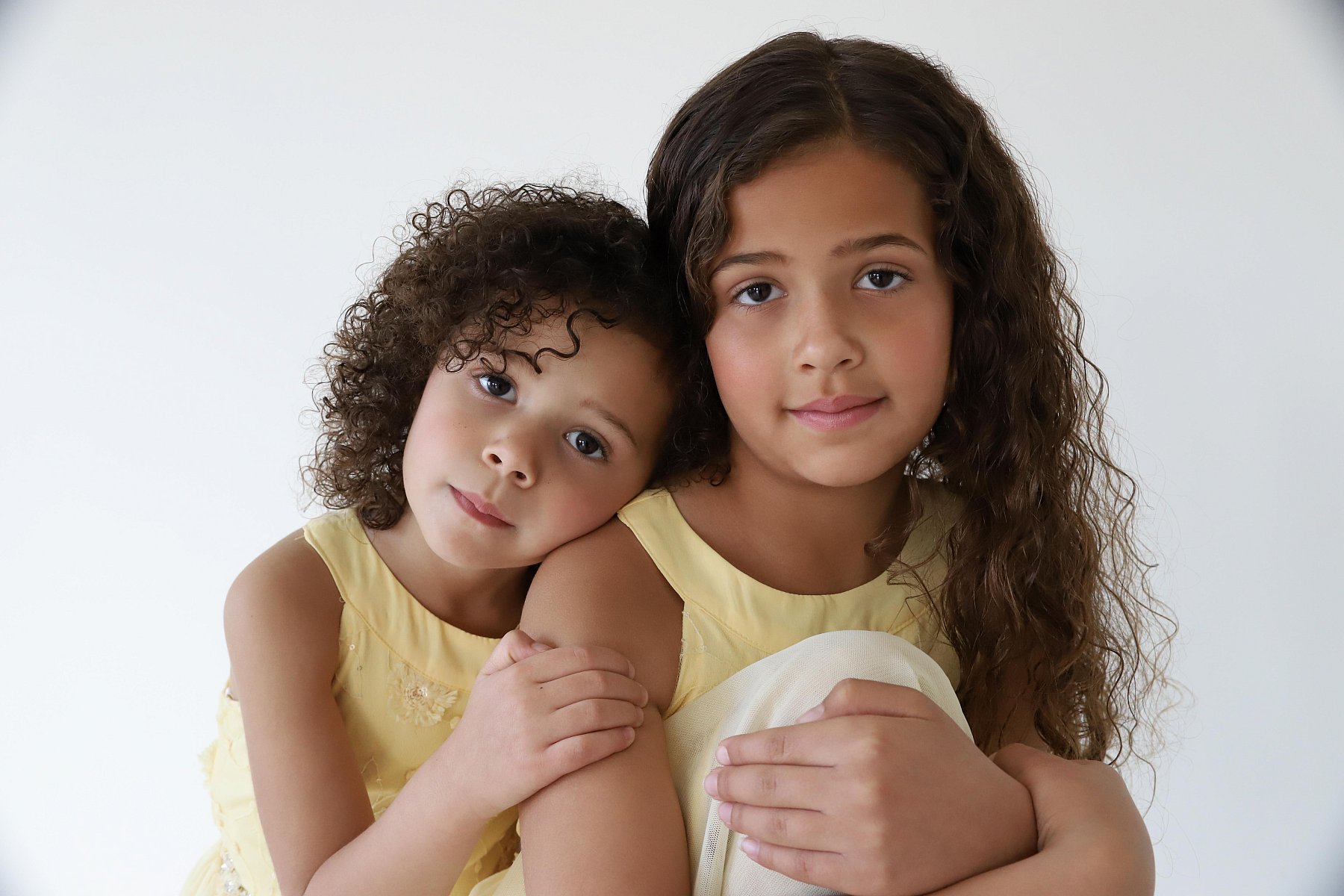 Two sisters in yellow dresses posing for siblings school portrait in Utah.