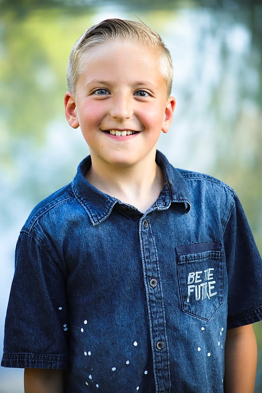 School portrait of elementary boy in blue shirt down outside in Utah County.